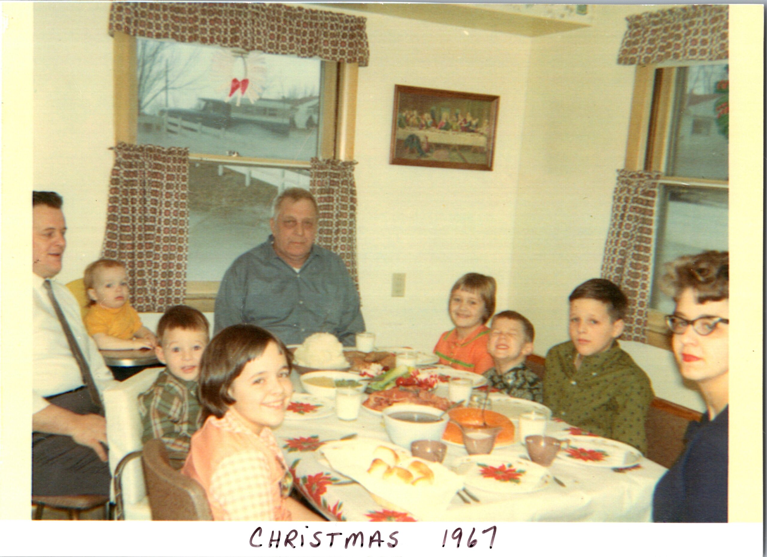Family and children seated around a table for a Christmas meal in a bright dining room (1967).